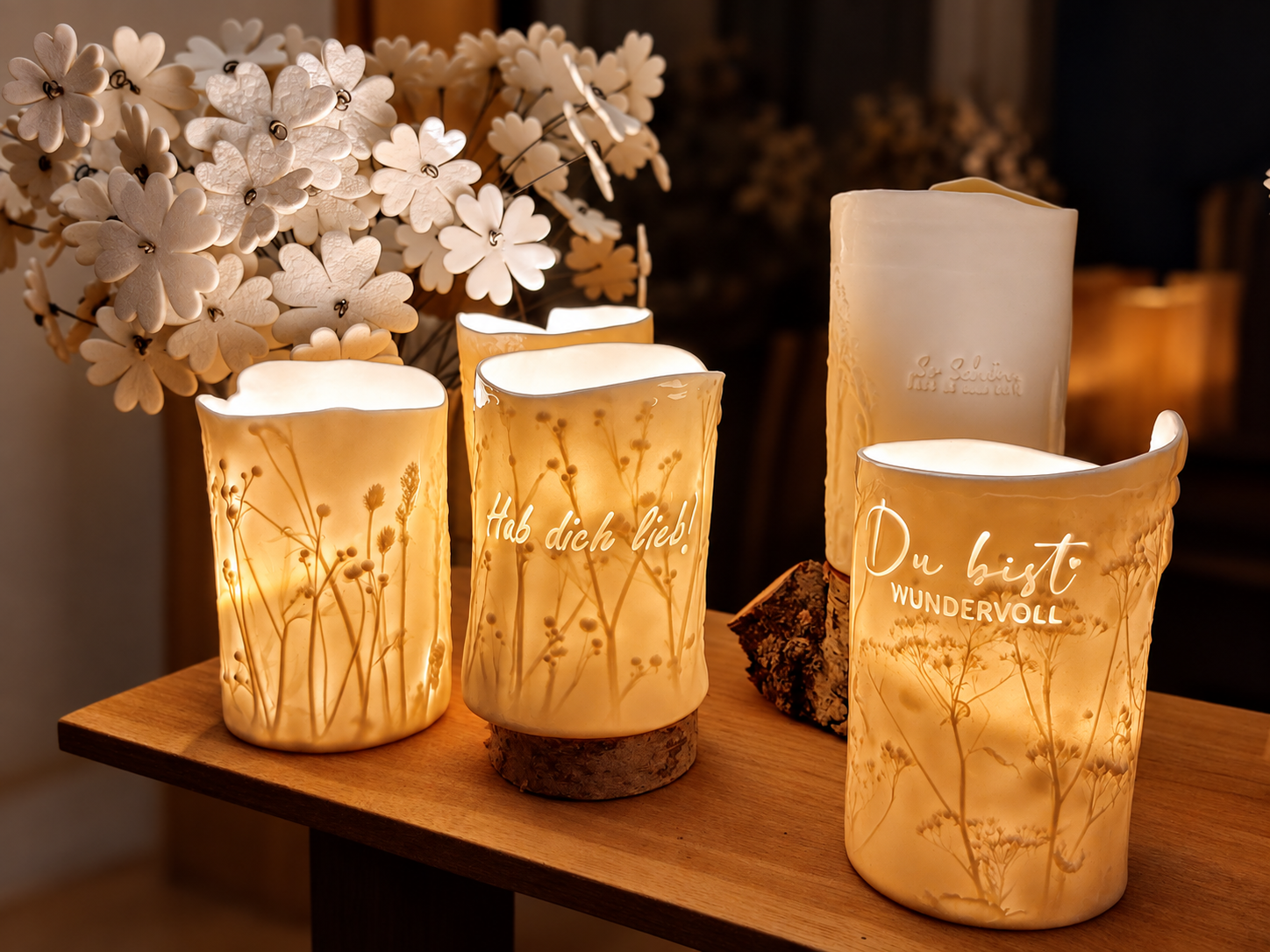 Warm leuchtende Keramik-Windlichter mit Pflanzenreliefs und weißen Keramikblumen